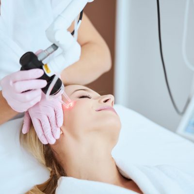 Relaxed serene blonde Caucasian female patient getting a skin laser treatment in a beauty salon